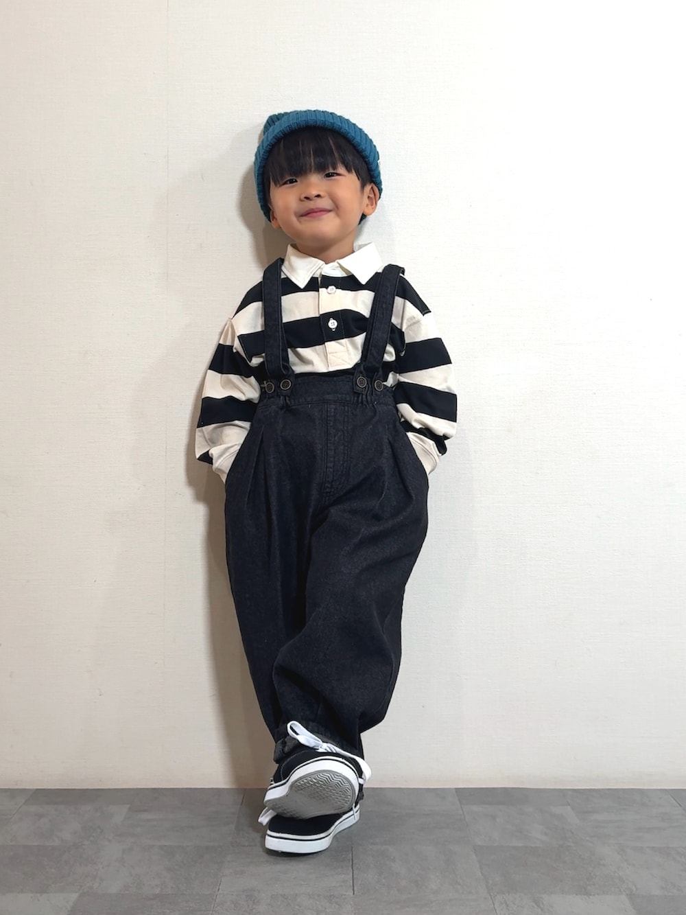 ブラック系のスニーカー、ブラック系のサロペット/オーバーオール、ホワイト系のポロシャツを着用したキッズの秋コーディネートの2枚目の写真