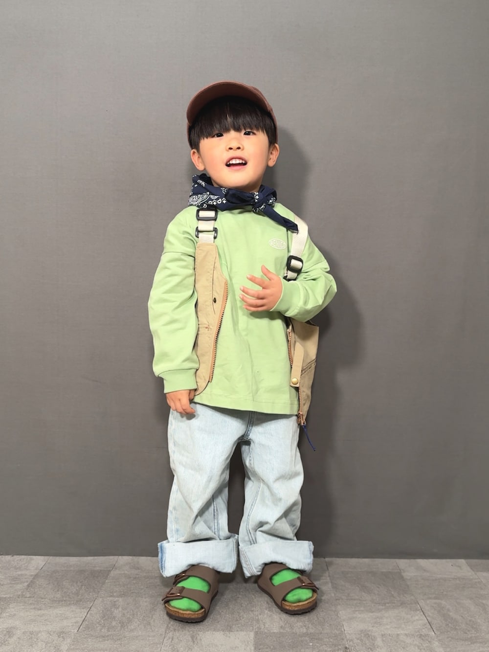 ベージュ系のベスト、グリーン系のTシャツ/カットソー、ブルー系のデニムパンツを着用したキッズの春コーディネートの3枚目の写真