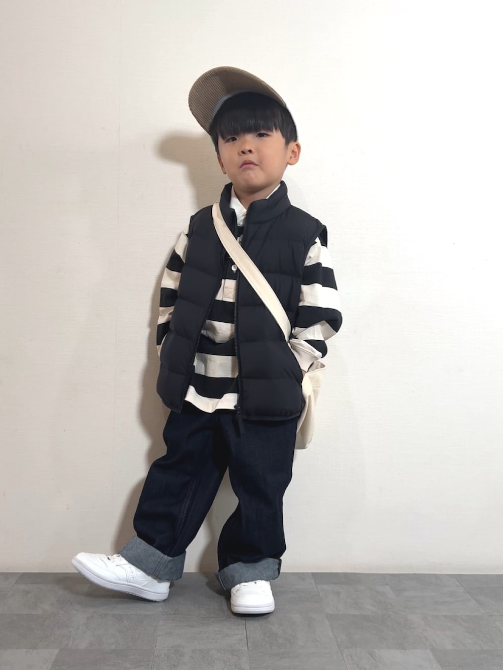 ホワイト系のスニーカー、ブラック系のベスト、ホワイト系のポロシャツを着用したキッズの秋コーディネートの3枚目の写真
