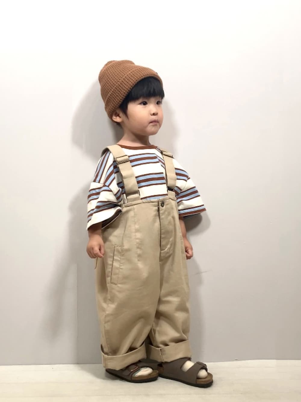 ベージュ系のTシャツ/カットソー、ベージュ系のサロペット/オーバーオール、ブラウン系のサンダルを着用したキッズの夏コーディネートの2枚目の写真