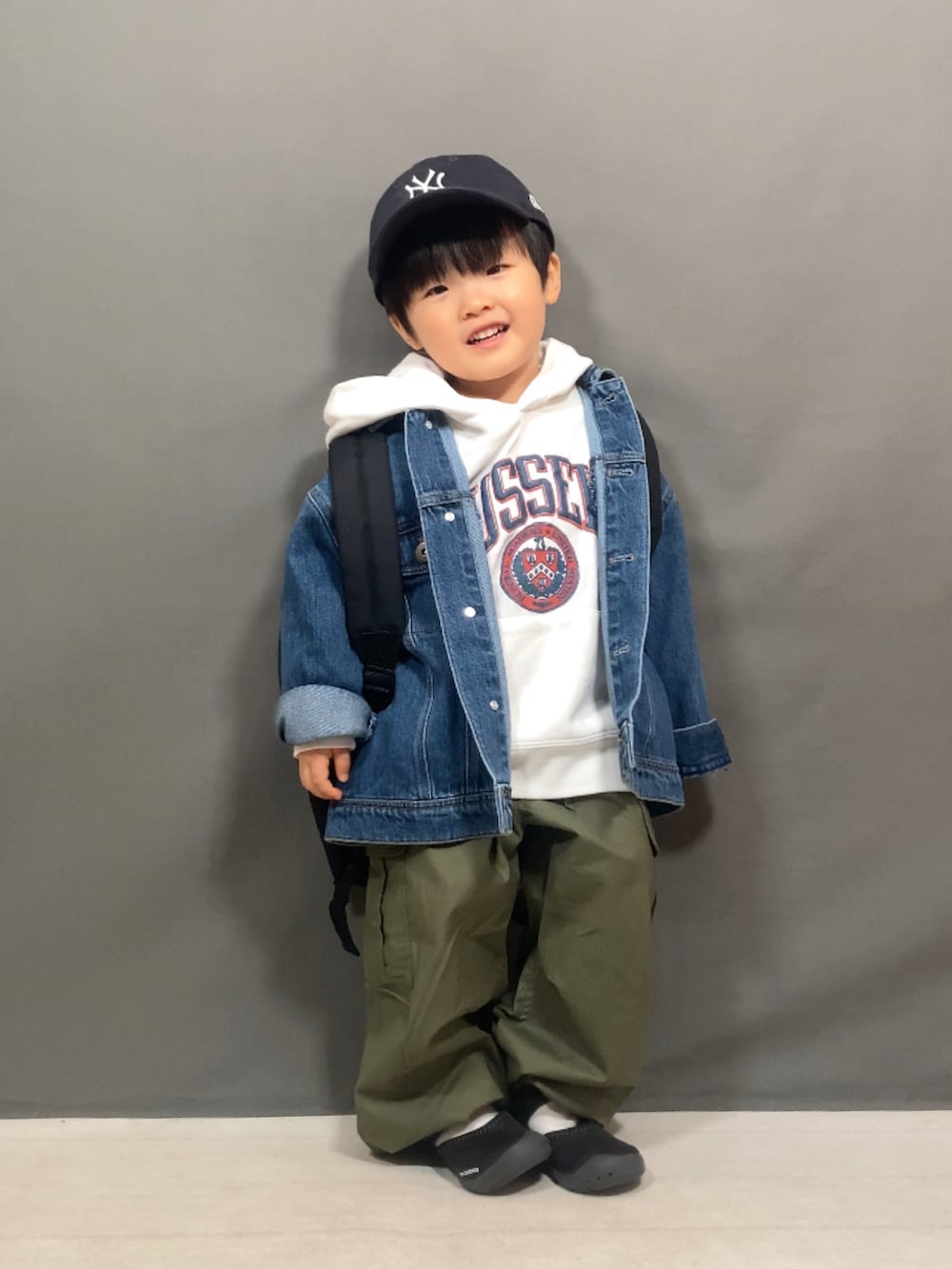ブルー系のデニムジャケット、ホワイト系のスウェット、グリーン系のカーゴパンツを着用したキッズの冬コーディネートの2枚目の写真
