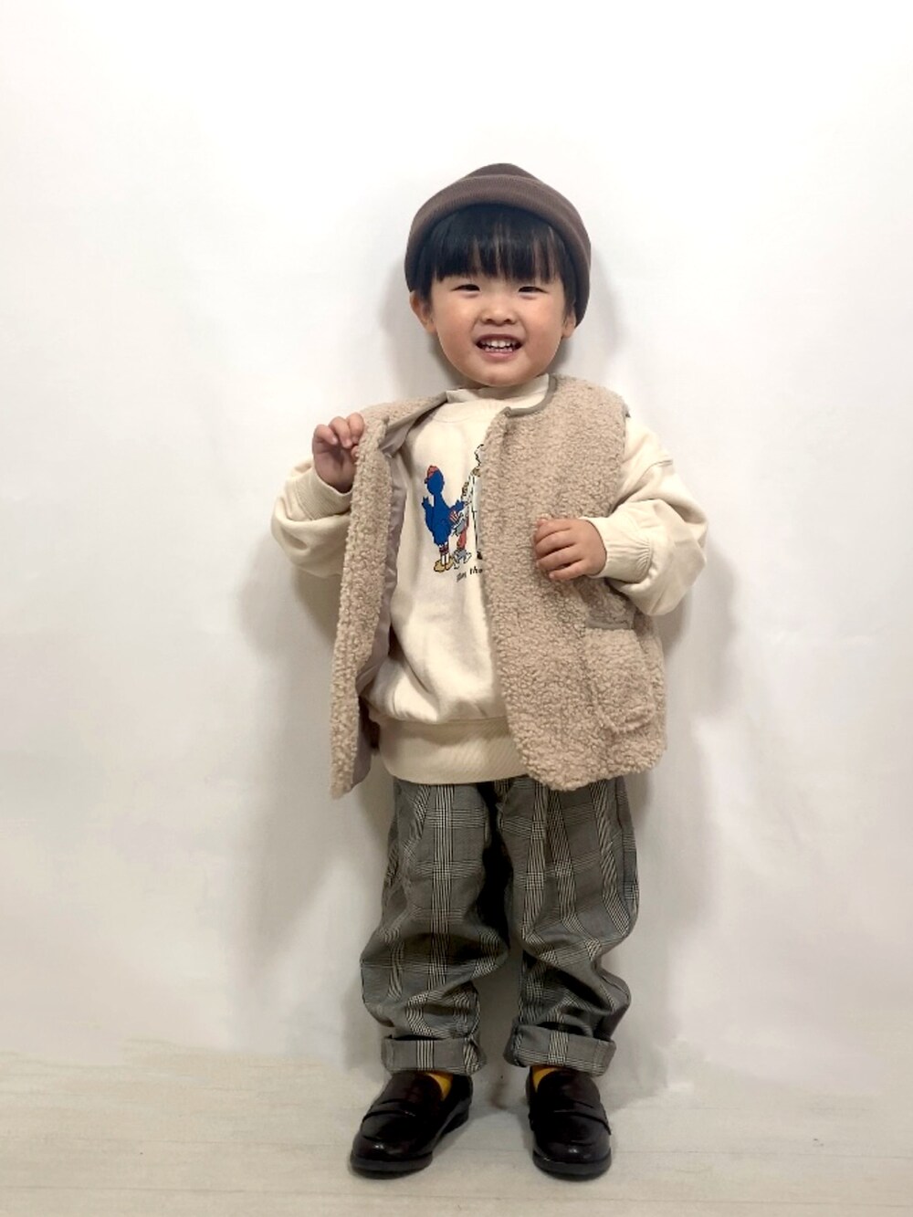 ベージュ系のベスト、ベージュ系のスウェット、ホワイト系のTシャツ/カットソーを着用したキッズの秋コーディネートの2枚目の写真