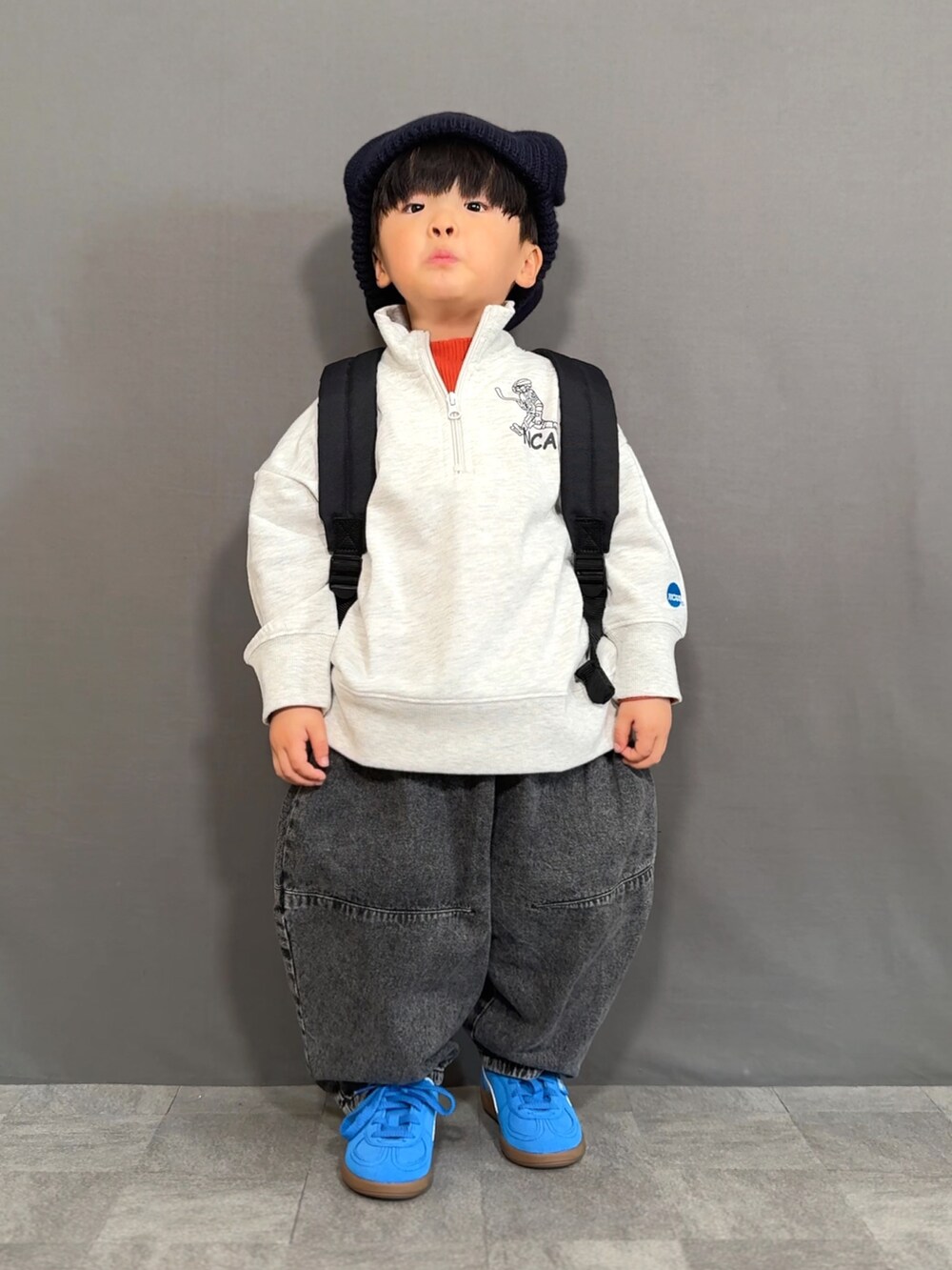 グレー系のスウェット、オレンジ系のTシャツ/カットソー、ブラック系のデニムパンツを着用したキッズの冬コーディネートの3枚目の写真