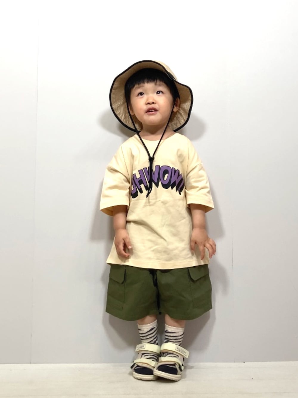 ベージュ系のTシャツ/カットソー、グリーン系のカーゴパンツ、ホワイト系のサンダルを着用したキッズの夏コーディネートの2枚目の写真