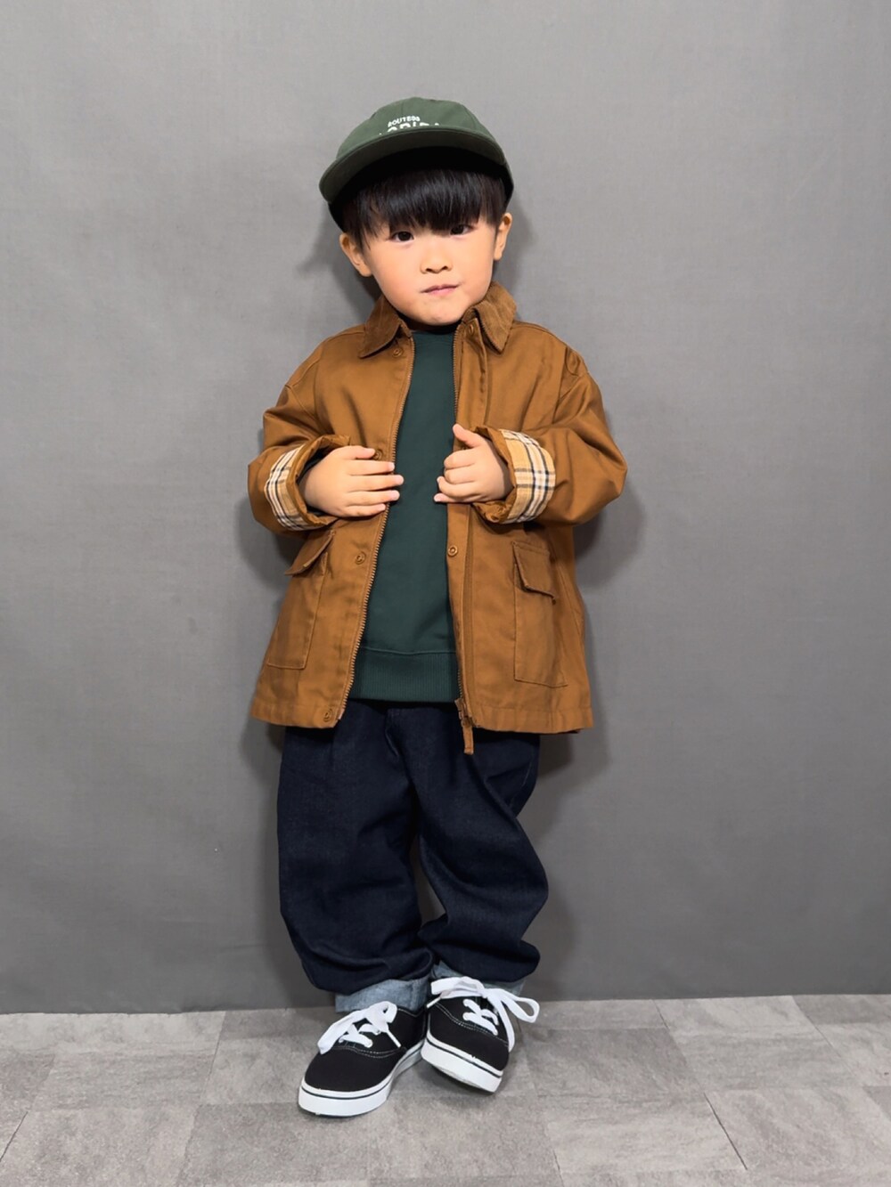 ブラウン系のジャケット/アウター、グリーン系のスウェット、ブルー系のデニムパンツを着用したキッズの秋コーディネートの2枚目の写真