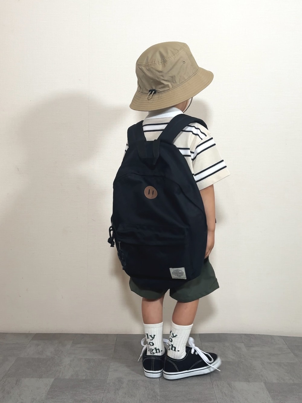 ベージュ系のポロシャツ、イエロー系のパンツ、ブラック系のバックパック/リュックを着用したキッズの夏コーディネートの3枚目の写真