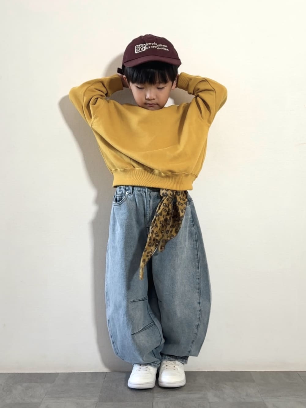 ブルー系のデニムパンツ、ホワイト系のスニーカー、イエロー系のスウェットを着用したキッズの秋コーディネートの2枚目の写真