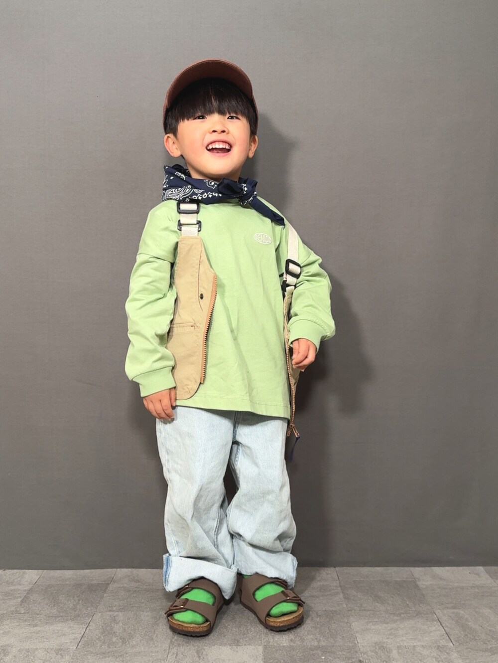 ベージュ系のベスト、グリーン系のTシャツ/カットソー、ブルー系のデニムパンツを着用したキッズの春コーディネートの4枚目の写真