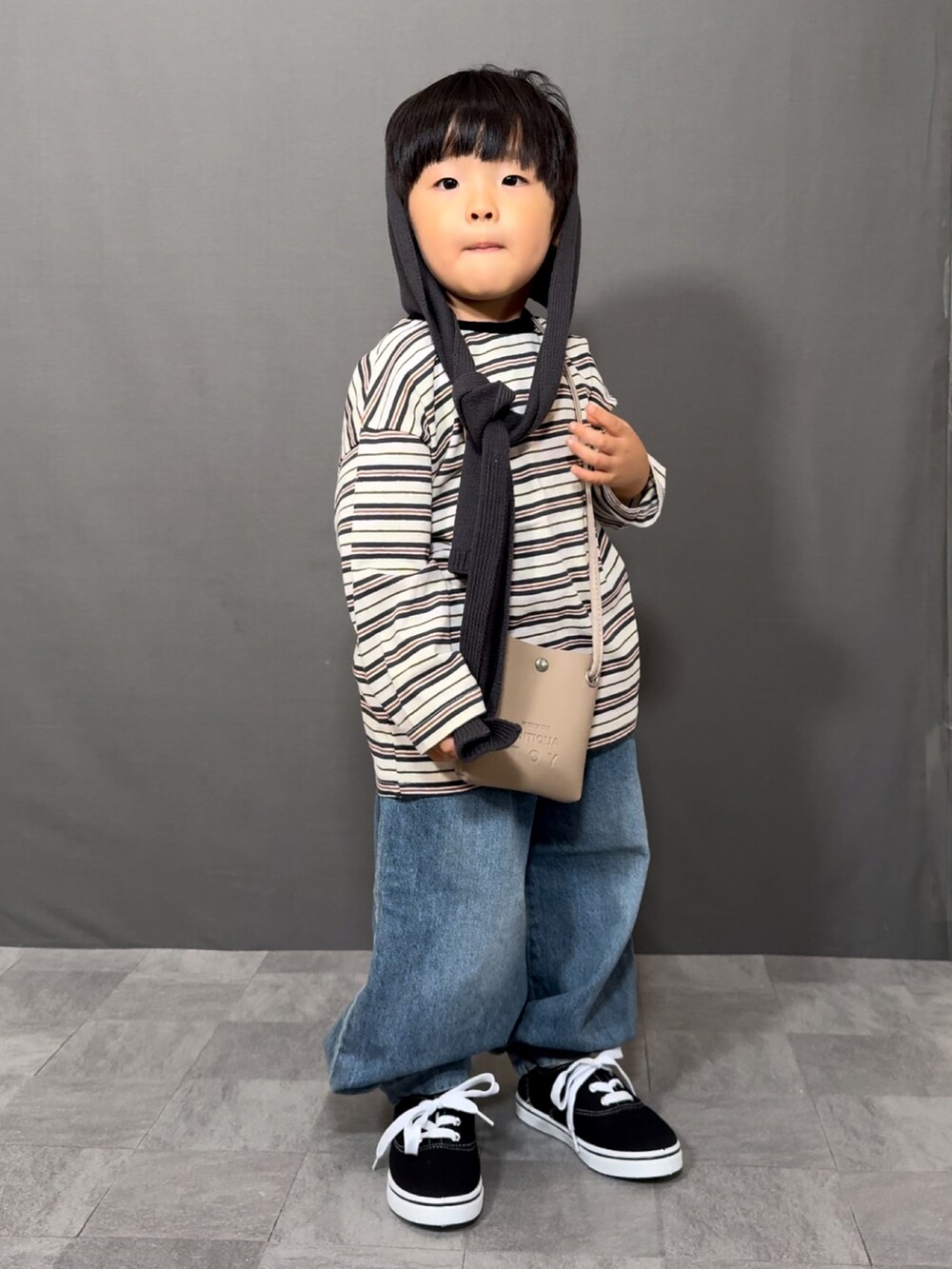 ホワイト系のトップス、ブルー系のデニムパンツ、ベージュ系のショルダーバッグを着用したキッズの秋コーディネートの2枚目の写真