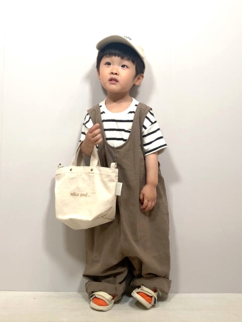 ホワイト系のTシャツ/カットソー、ブラウン系のオールインワン・サロペット、ホワイト系のショルダーバッグを着用したキッズの夏コーディネートの2枚目の写真