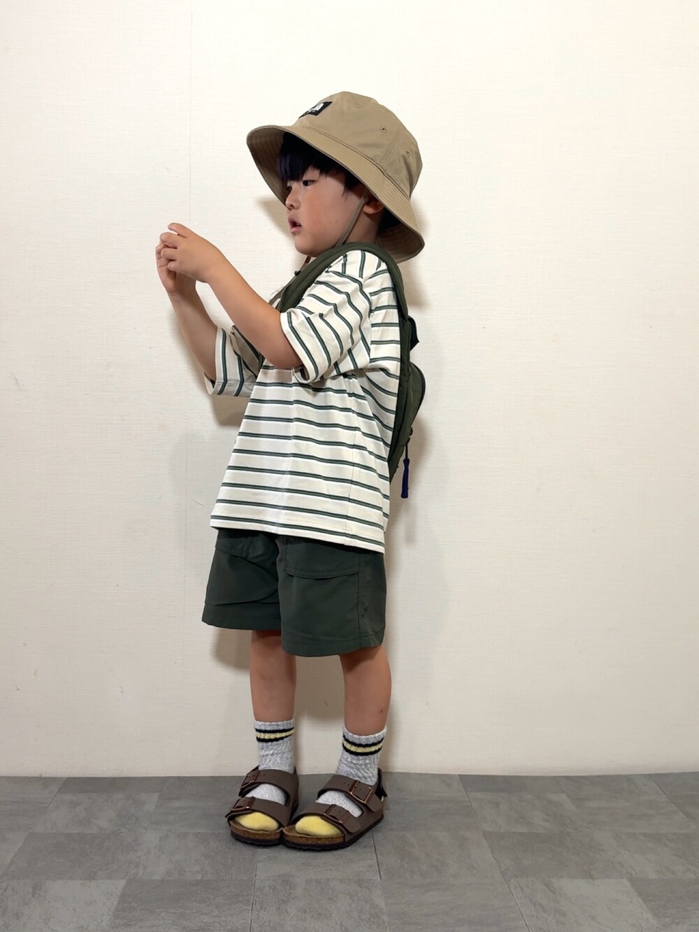 ベージュ系のトップス、イエロー系のパンツ、グリーン系のボディバッグ/ウエストポーチを着用したキッズの夏コーディネートの3枚目の写真