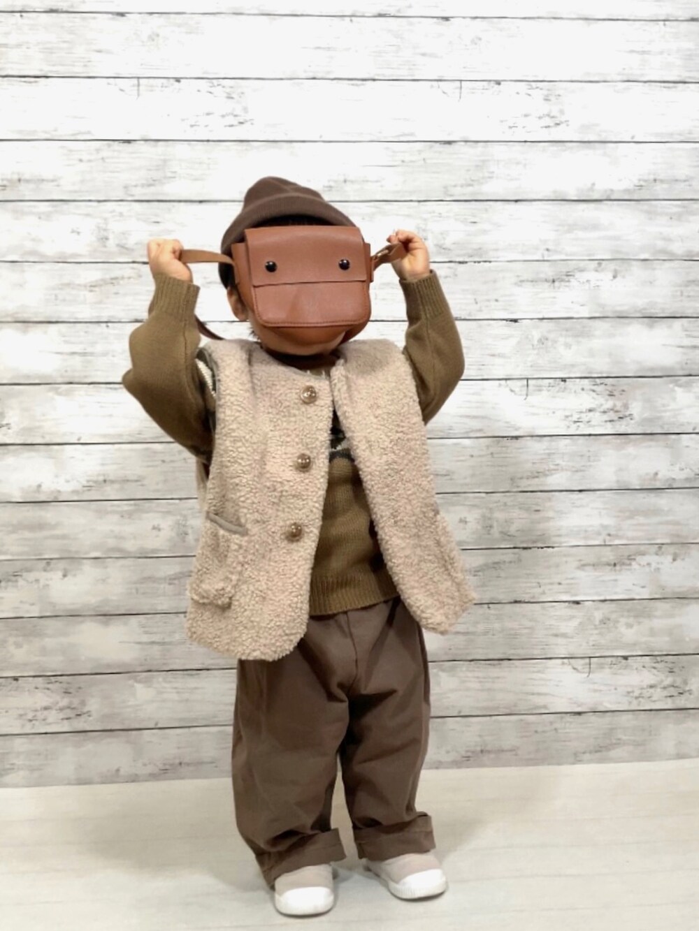 ベージュ系のベスト、ブラウン系のニット/セーター、ブラウン系のチノパンツを着用したキッズの冬コーディネートの3枚目の写真
