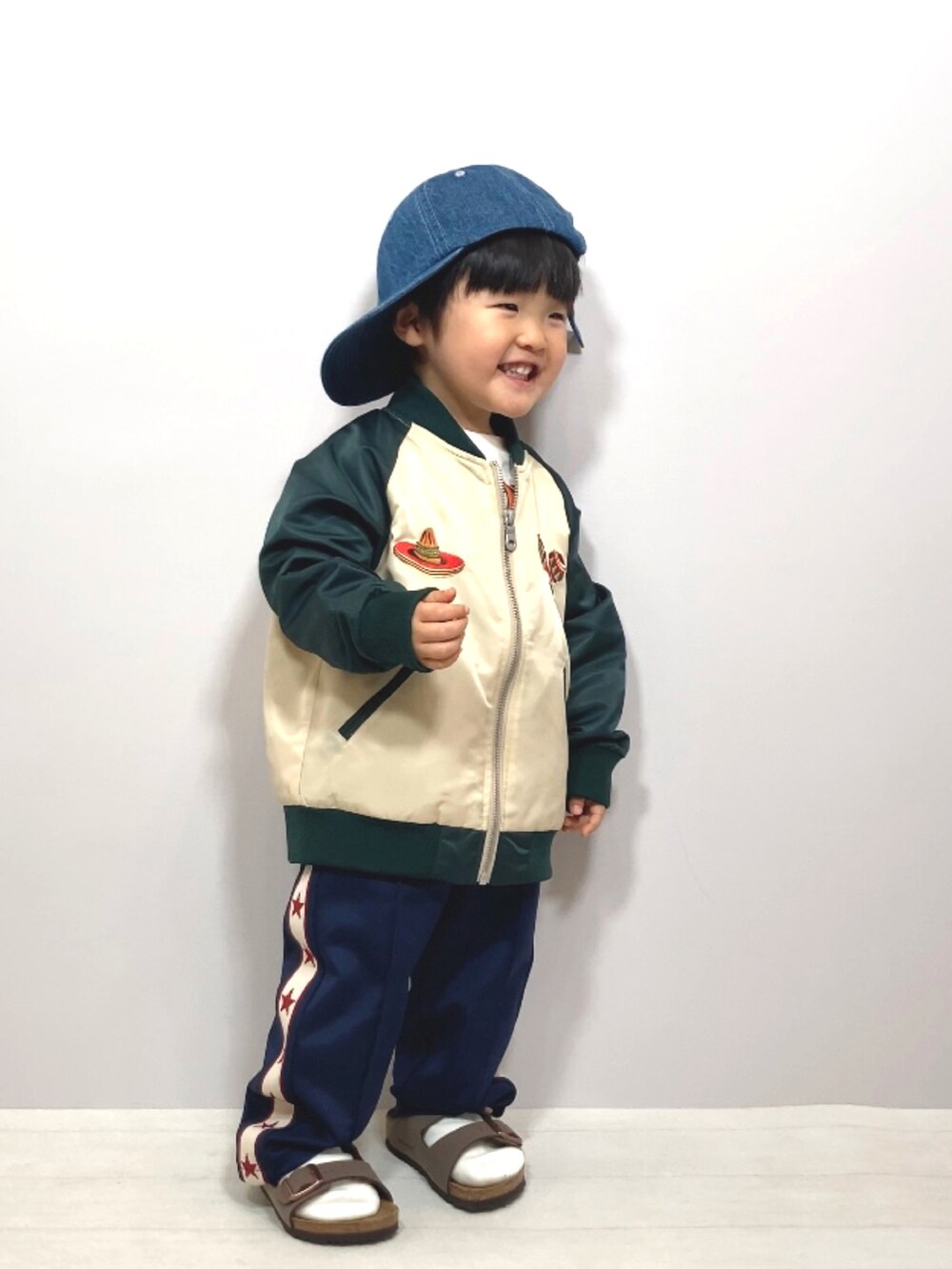 グリーン系のブルゾン、ホワイト系のTシャツ/カットソー、ブルー系のその他パンツを着用したキッズの春コーディネートの2枚目の写真