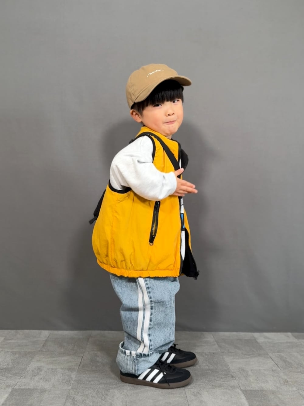 「ベスト、スウェット、デニム、スニーカー、キャップ、ショルダーバッグ、お出かけコーデ、ワイドパンツ、レイヤードスタイル、ストリート」|「LOWRYS FARMのリバーシブルベスト 145813(ベスト、イエロー系)」を使った、YU⭐︎さん(キッズ・90cm)の冬コーディネートの4枚目の写真
