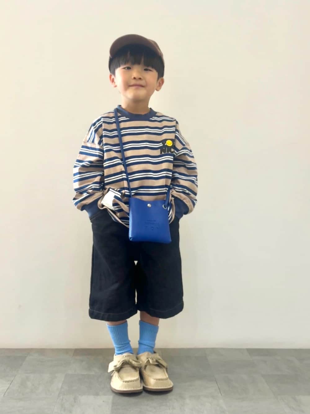 ブルー系のTシャツ/カットソー、ベージュ系のモカシン/デッキシューズ、ブルー系のショルダーバッグを着用したキッズの春コーディネートの3枚目の写真