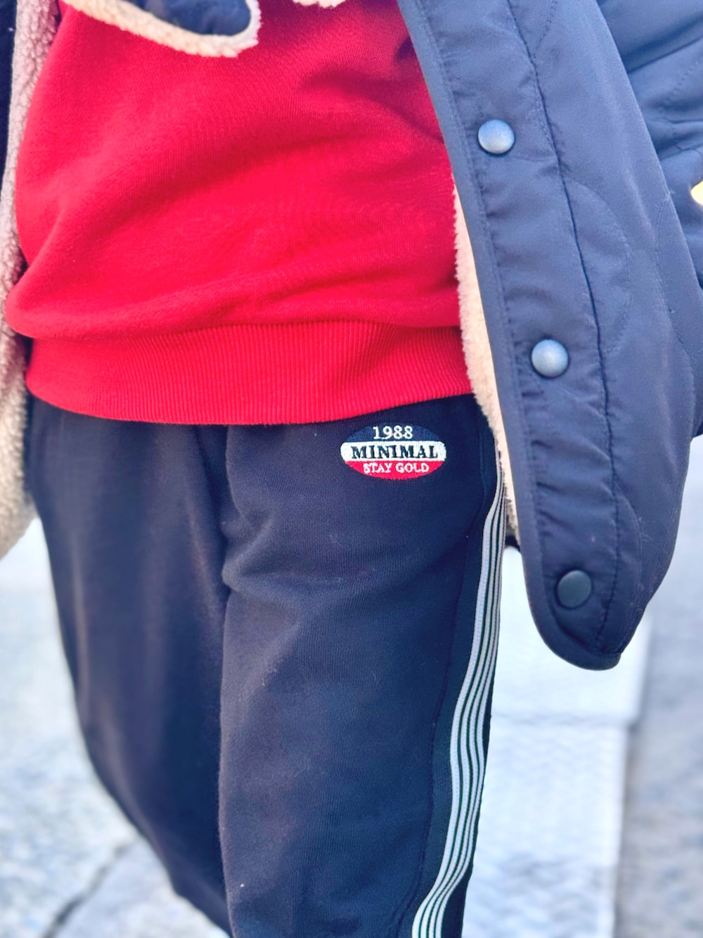 オレンジ系のスウェット、ブラック系のブルゾン、ブラック系のスウェットパンツを着用したキッズの秋コーディネートの4枚目の写真