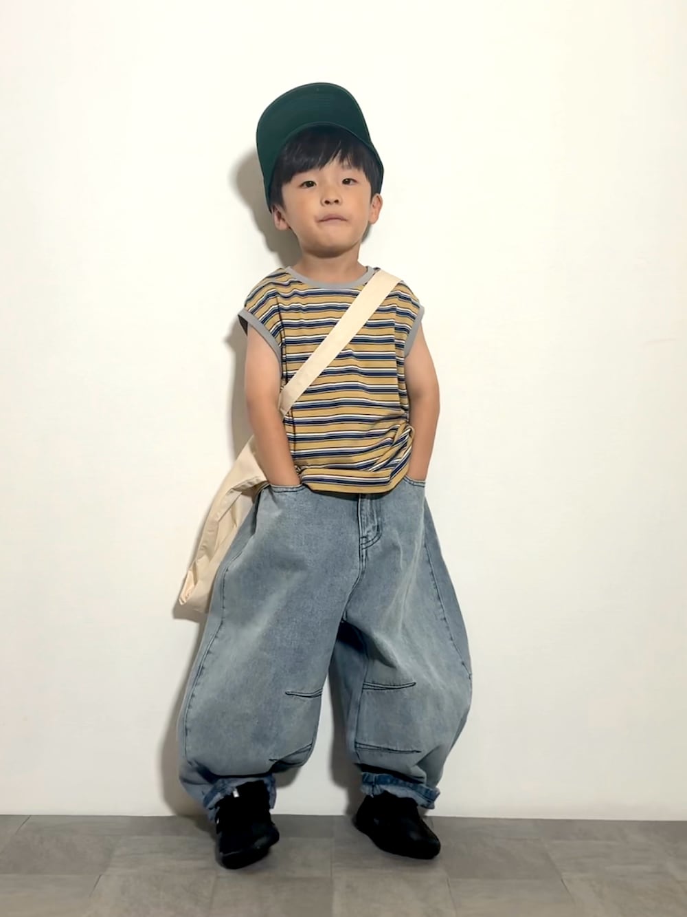 ブルー系のデニムパンツ、ベージュ系のトートバッグ、イエロー系のタンクトップを着用したキッズの夏コーディネートの2枚目の写真