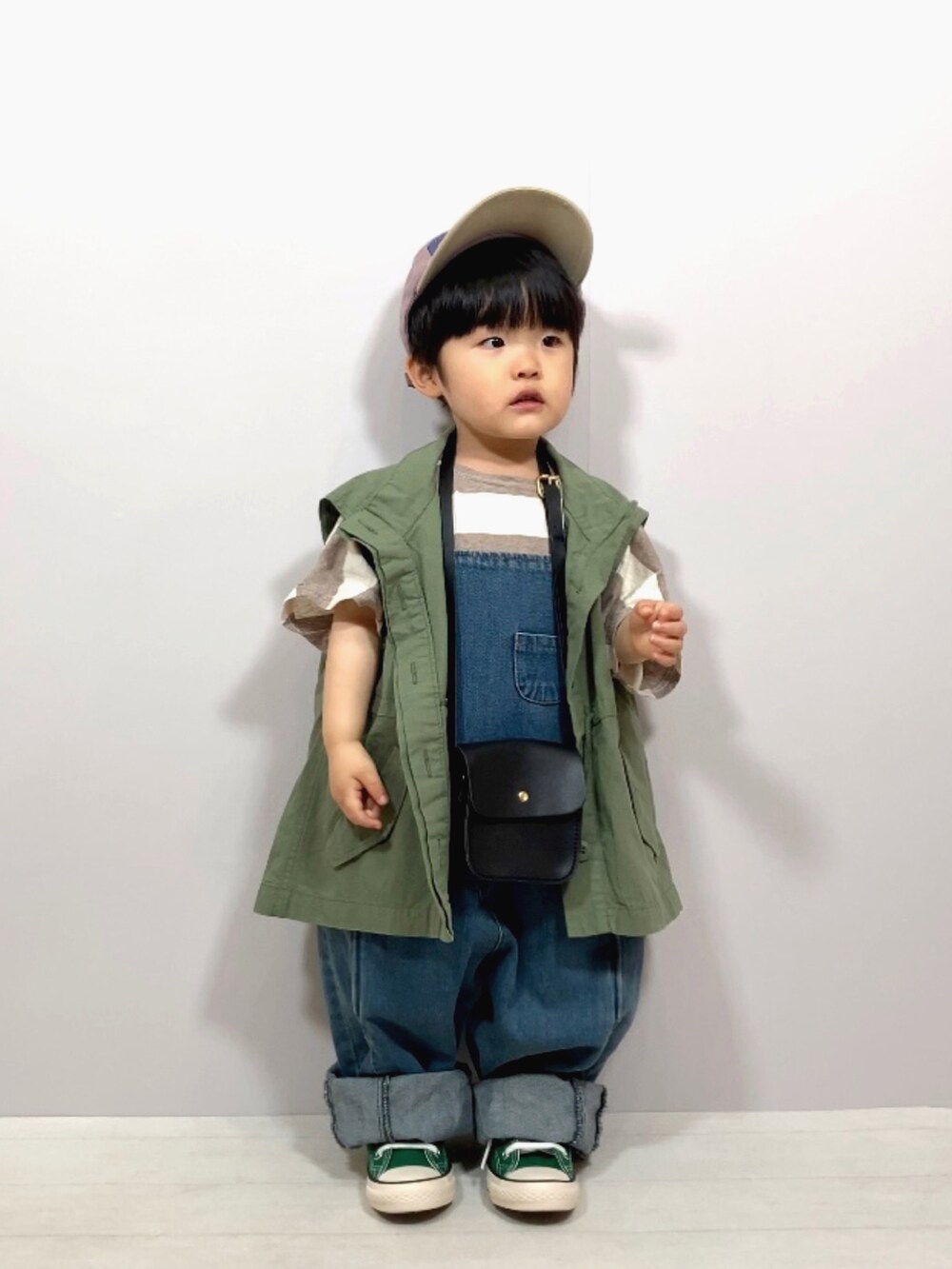 グリーン系のベスト、ベージュ系のTシャツ/カットソー、ブルー系のオールインワン・サロペットを着用したキッズの春コーディネートの2枚目の写真