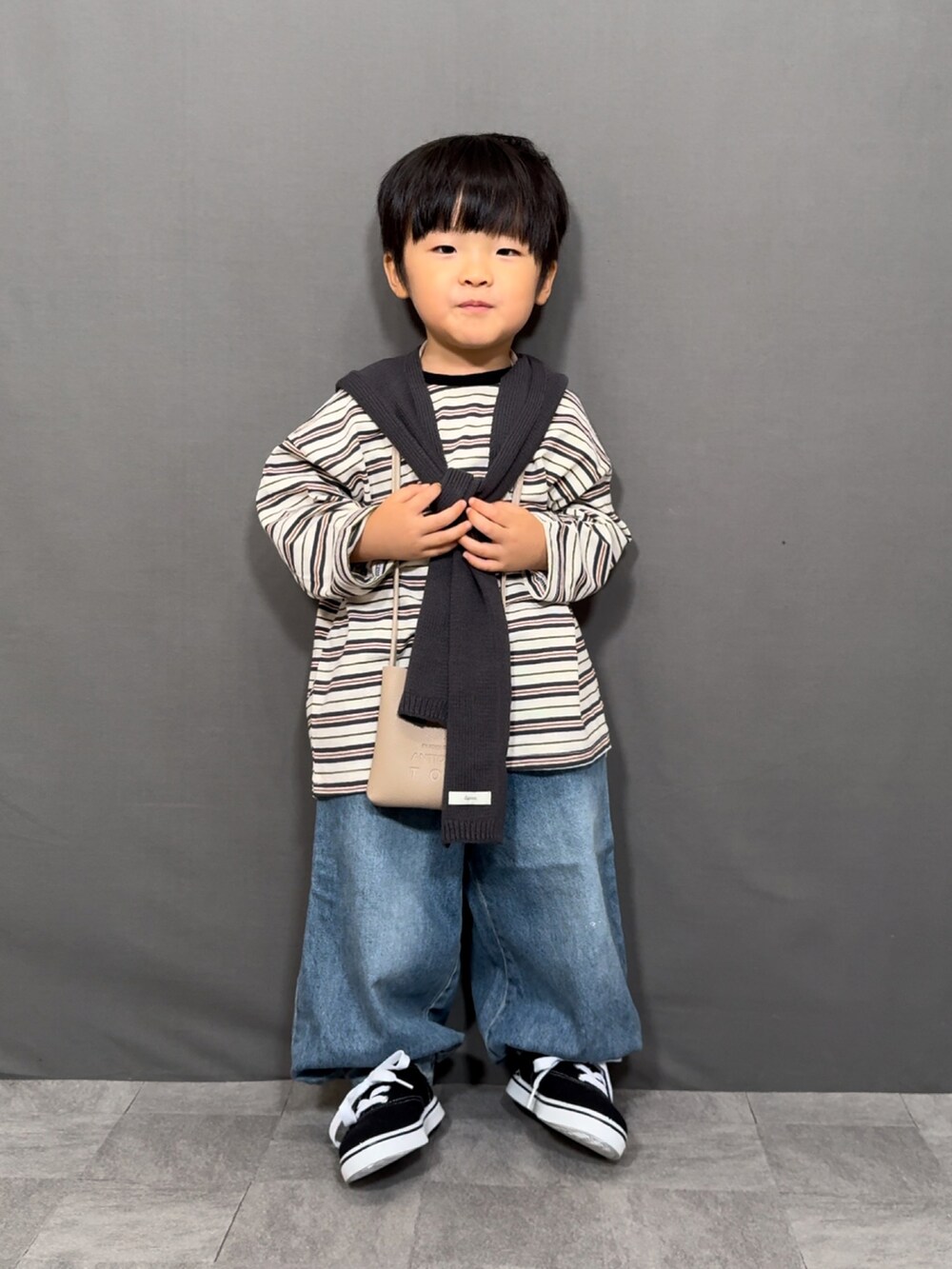 ホワイト系のトップス、ブルー系のデニムパンツ、ベージュ系のショルダーバッグを着用したキッズの秋コーディネートの3枚目の写真