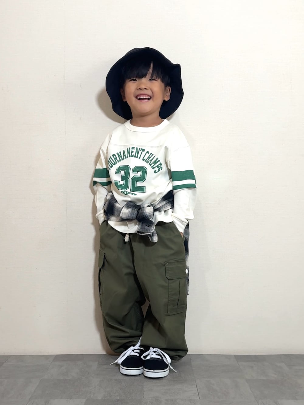 ブラック系のスニーカー、グリーン系のカーゴパンツ、ホワイト系のトップスを着用したキッズの夏コーディネートの2枚目の写真