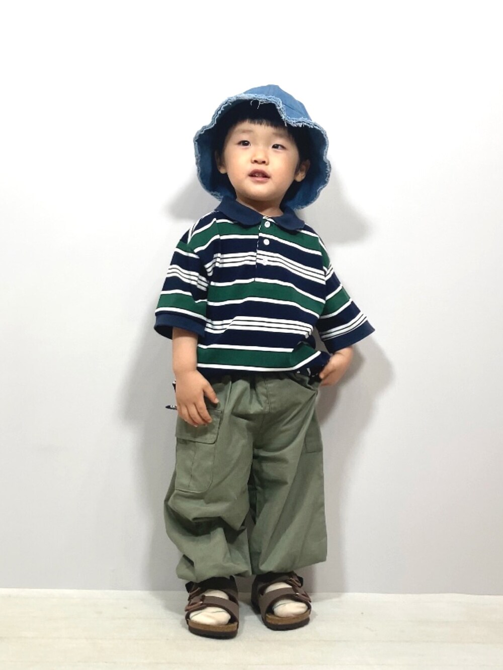 ブルー系のポロシャツ、グリーン系のカーゴパンツ、ブラウン系のサンダルを着用したキッズの夏コーディネートの2枚目の写真