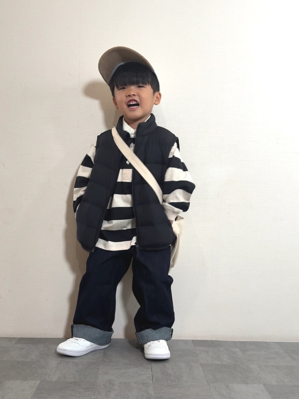 ホワイト系のスニーカー、ブラック系のベスト、ホワイト系のポロシャツを着用したキッズの秋コーディネートの2枚目の写真