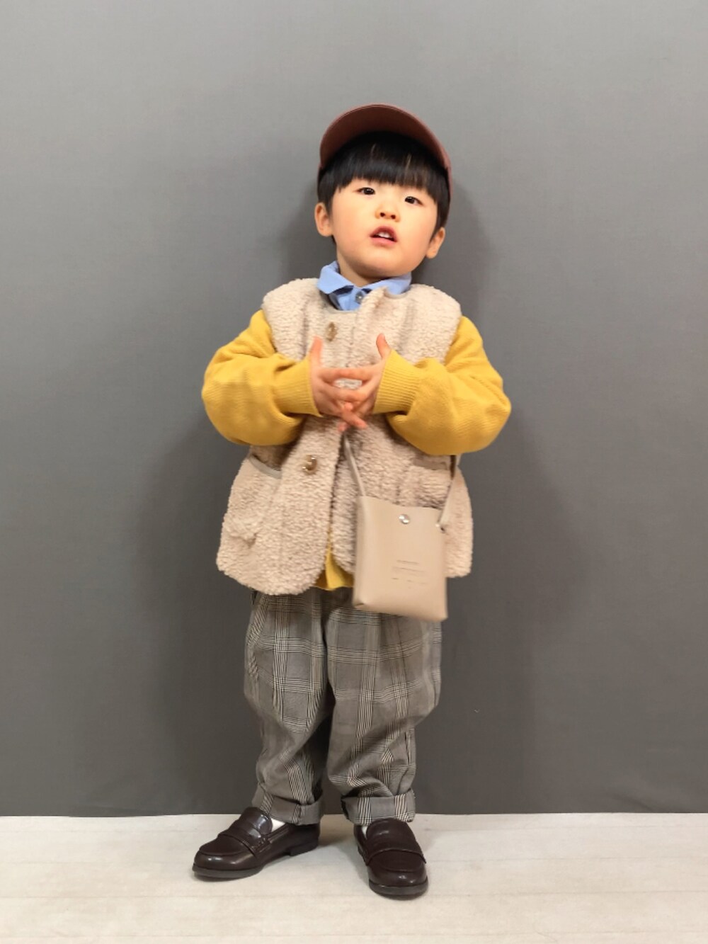 ベージュ系のベスト、イエロー系のカーディガン/ボレロ、ブルー系のシャツ/ブラウスを着用したキッズの冬コーディネートの3枚目の写真