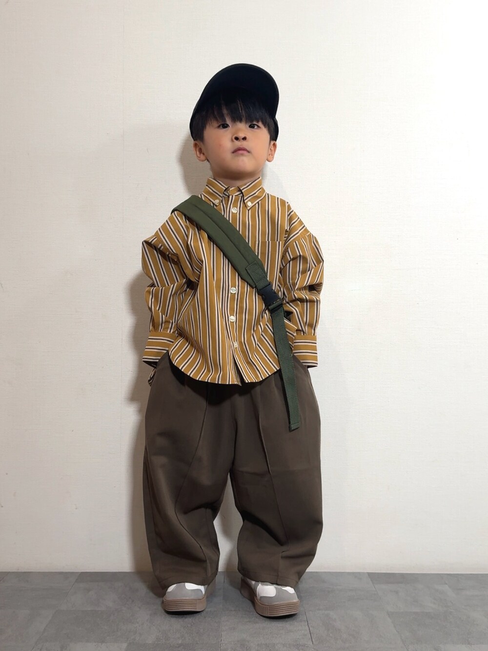 イエロー系のシャツ/ブラウス、ブラウン系のスラックス、グリーン系のボディバッグ/ウエストポーチを着用したキッズの秋コーディネートの2枚目の写真