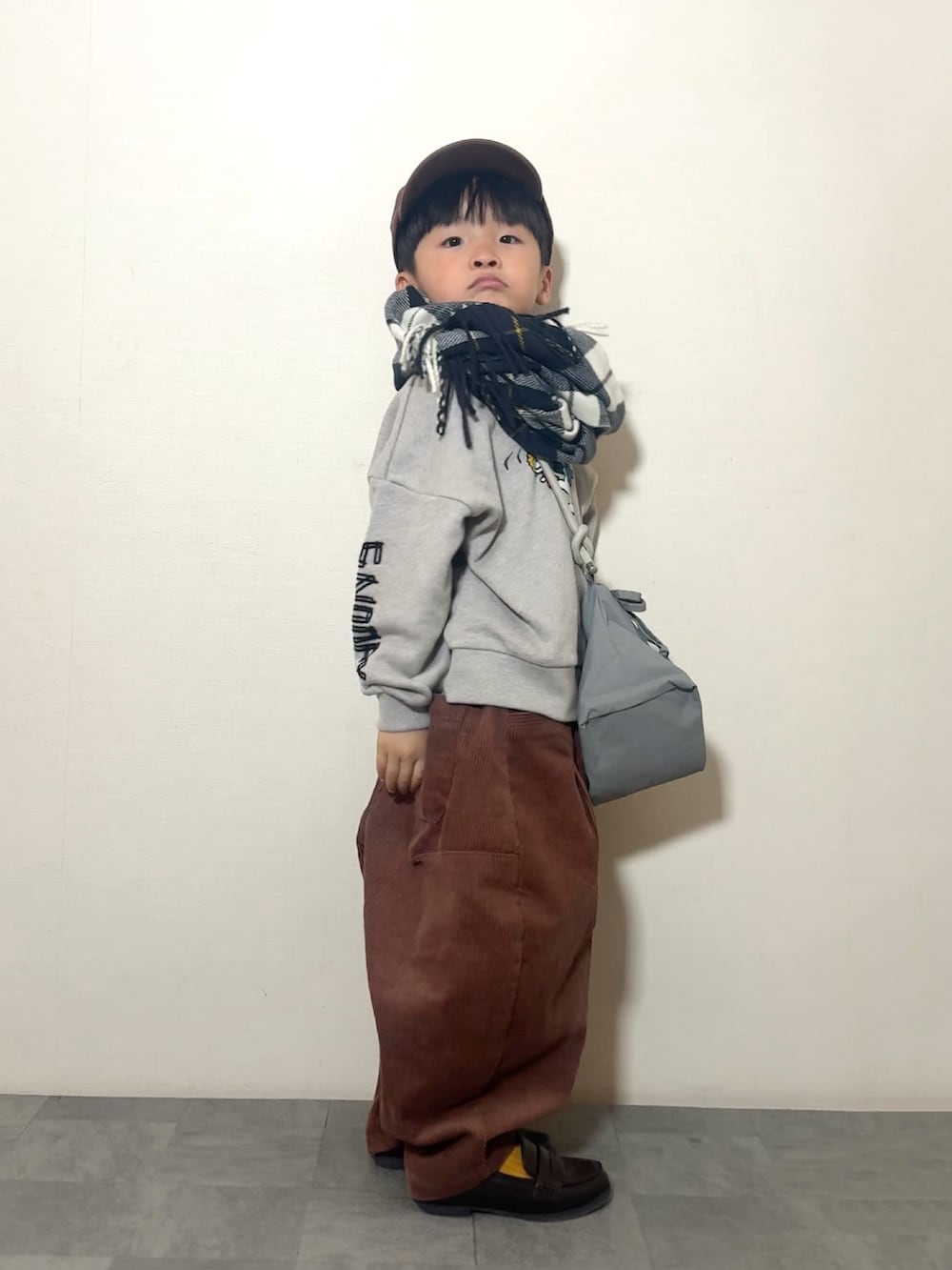 ブラウン系のその他パンツ、ブラウン系のローファー、グレー系のショルダーバッグを着用したキッズの冬コーディネートの2枚目の写真