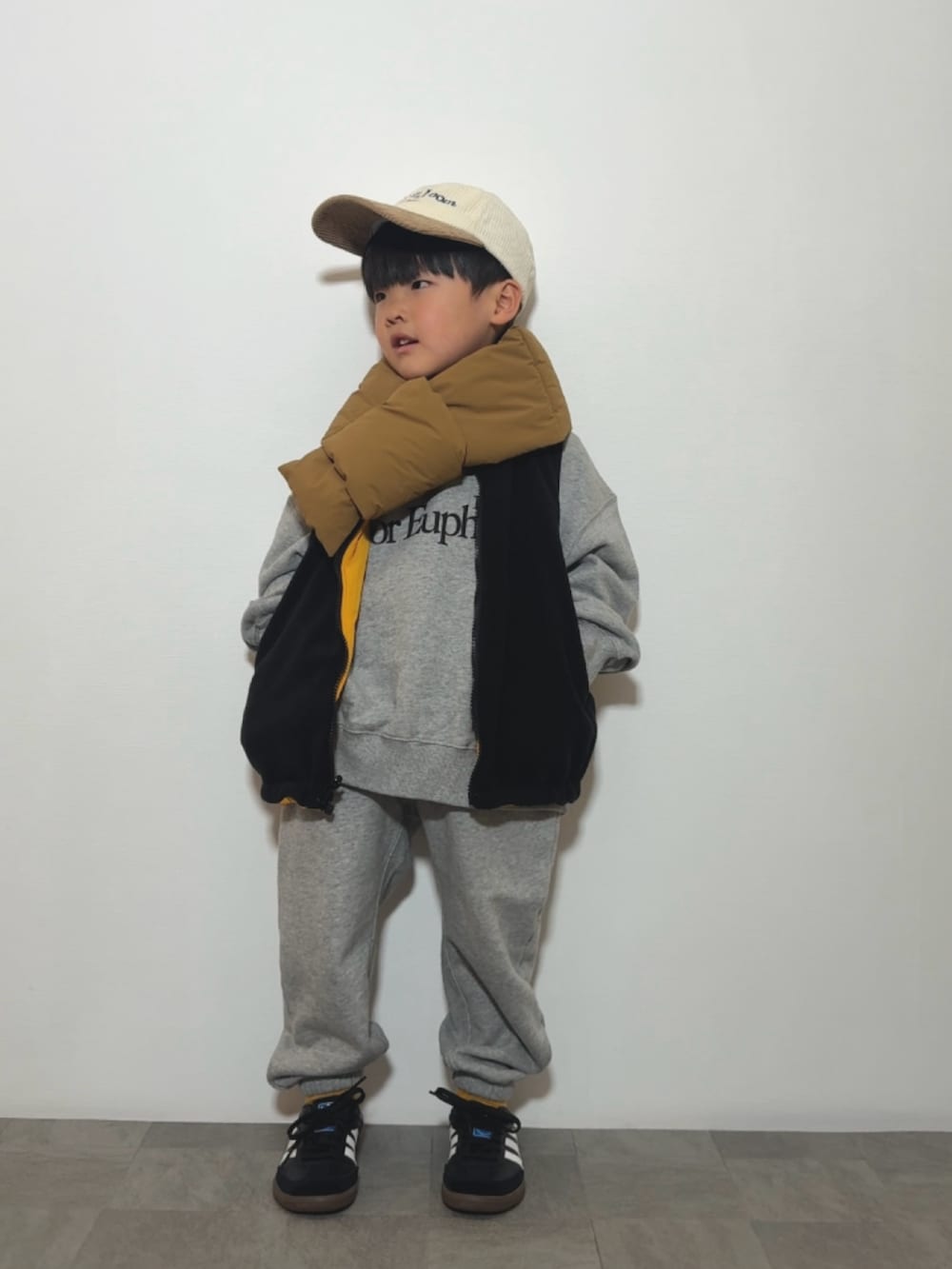 グレー系のスウェット、イエロー系のベスト、グレー系のスウェットパンツを着用したキッズの冬コーディネートの2枚目の写真