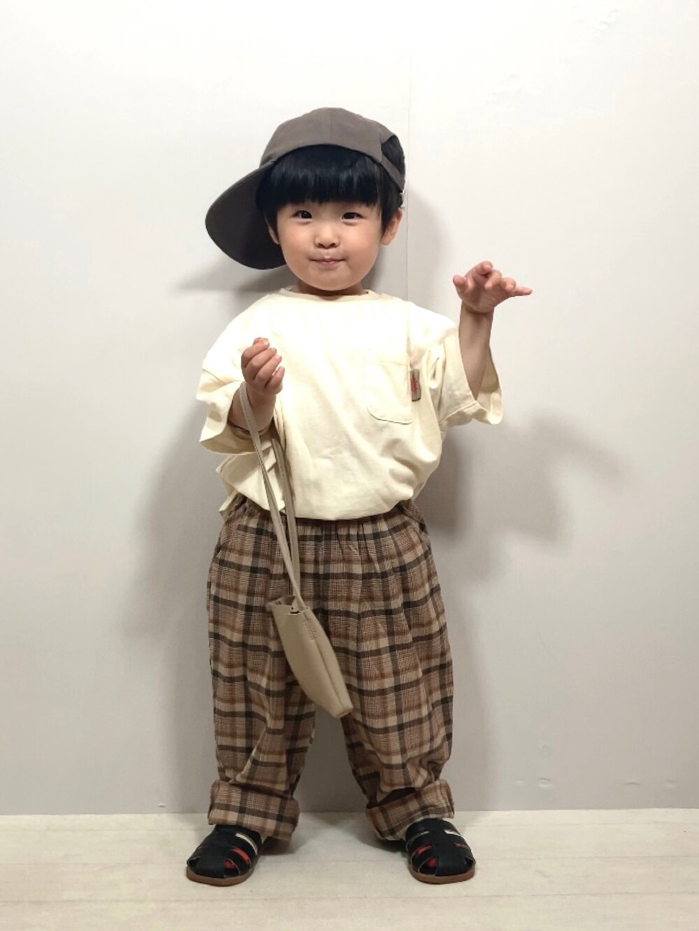 ホワイト系のTシャツ/カットソー、ブラウン系のパンツ、ベージュ系のショルダーバッグを着用したキッズの夏コーディネートの3枚目の写真