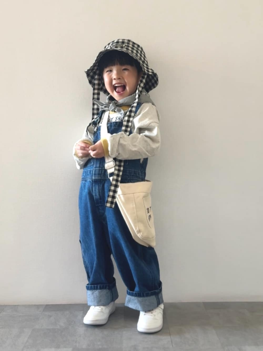 イエロー系のTシャツ/カットソー、ブルー系のサロペット/オーバーオール、ホワイト系のショルダーバッグを着用したキッズの冬コーディネートの3枚目の写真