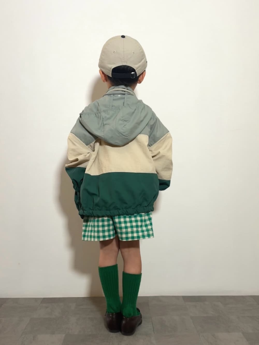 グレー系のショルダーバッグ、ブラウン系のローファー、グリーン系のナイロンジャケットを着用したキッズの春コーディネートの2枚目の写真