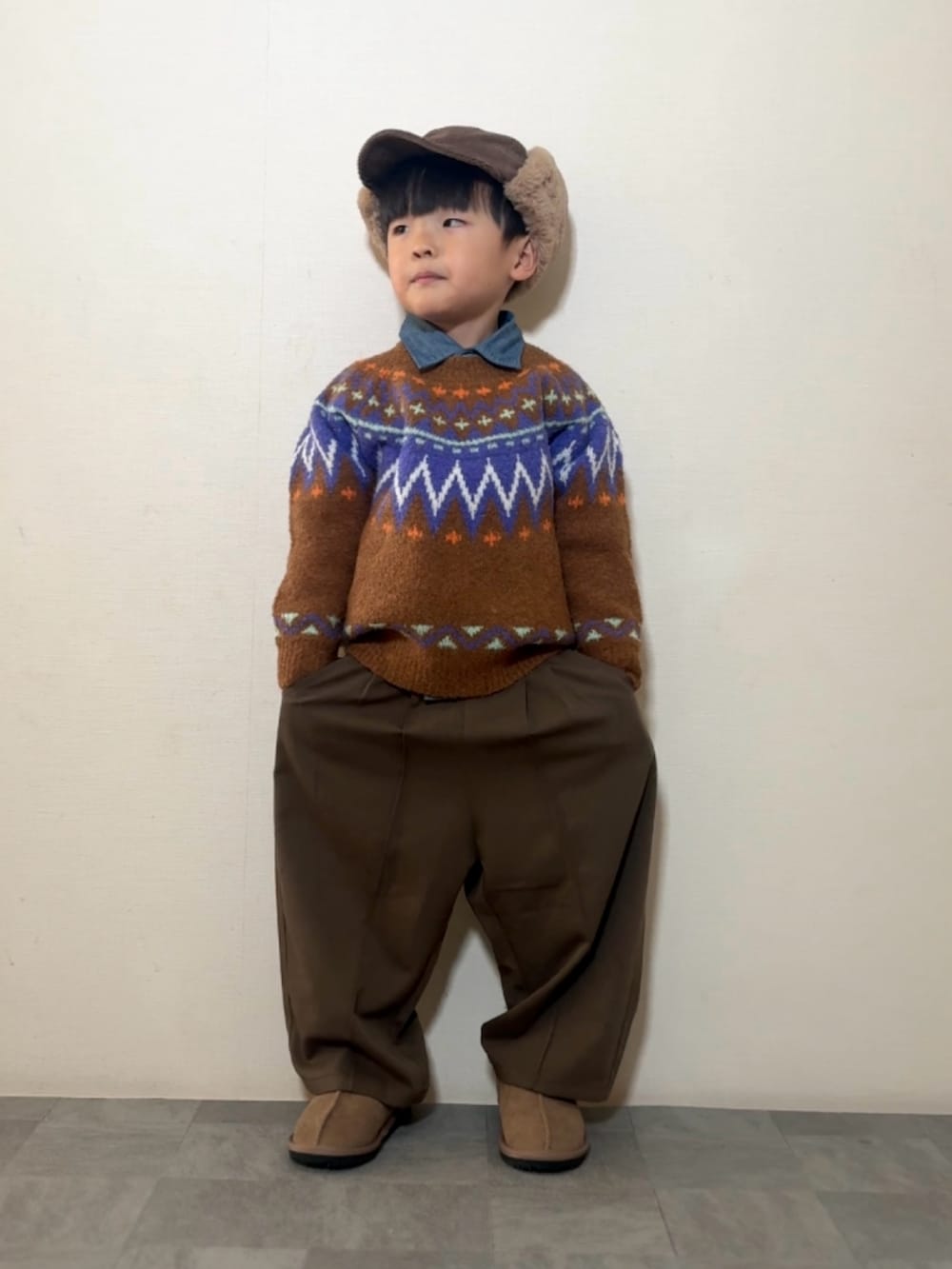 ブラウン系のニット/セーター、ブラウン系のスラックス、イエロー系のブーツを着用したキッズの冬コーディネートの2枚目の写真