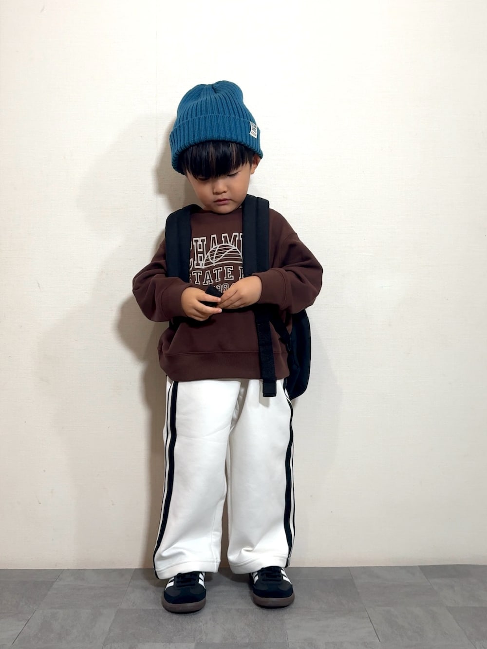 ブラック系のスニーカー、ブラック系のバックパック/リュック、ブラウン系のスウェットを着用したキッズの秋コーディネートの4枚目の写真