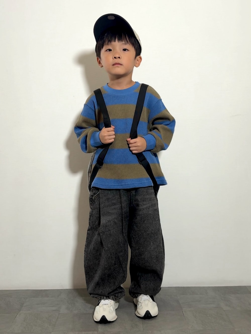 グレー系のバックパック/リュック、ブラック系のその他パンツ、ホワイト系のスニーカーを着用したキッズの秋コーディネートの2枚目の写真