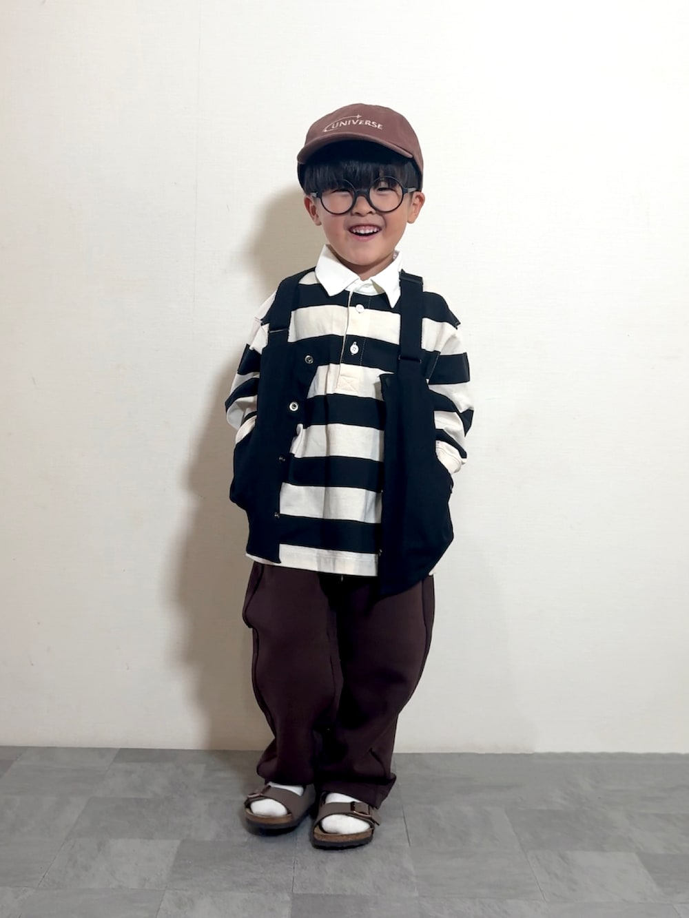 ブラウン系のサンダル、ブラック系のベスト、ホワイト系のポロシャツを着用したキッズの夏コーディネートの3枚目の写真