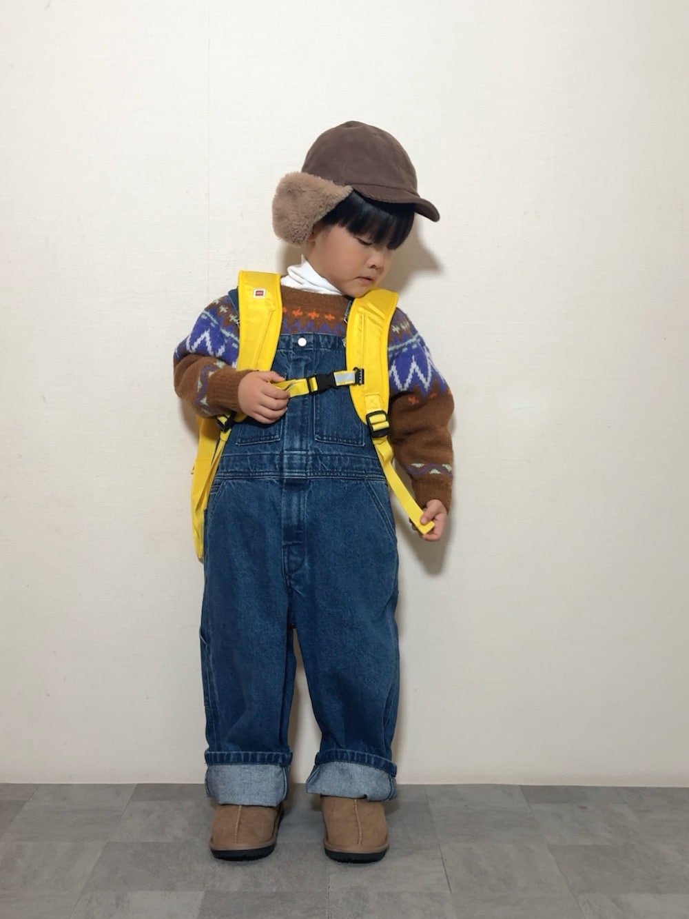 イエロー系のブーツ、イエロー系のバックパック/リュック、ブラウン系のニット/セーターを着用したキッズの冬コーディネートの4枚目の写真