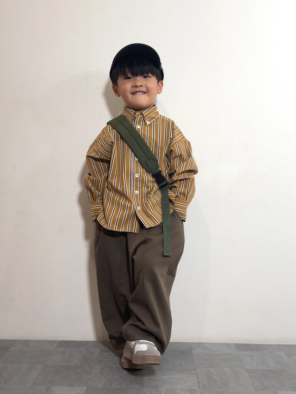 イエロー系のシャツ/ブラウス、ブラウン系のスラックス、グリーン系のボディバッグ/ウエストポーチを着用したキッズの秋コーディネートの3枚目の写真