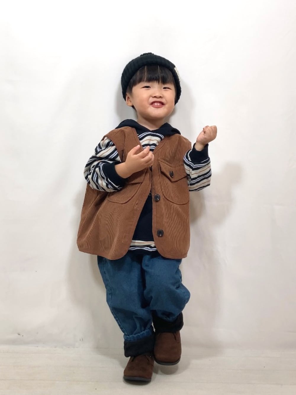 ブラウン系のベスト、ブラック系のパーカー、ブルー系のデニムパンツを着用したキッズの秋コーディネートの4枚目の写真
