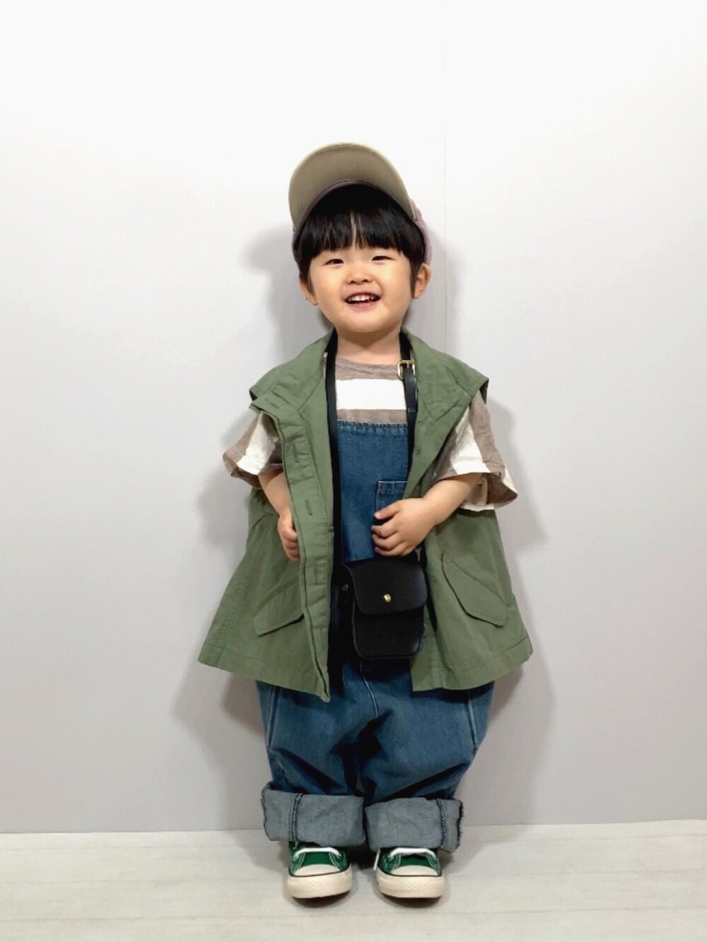 グリーン系のベスト、ベージュ系のTシャツ/カットソー、ブルー系のオールインワン・サロペットを着用したキッズの春コーディネートの3枚目の写真