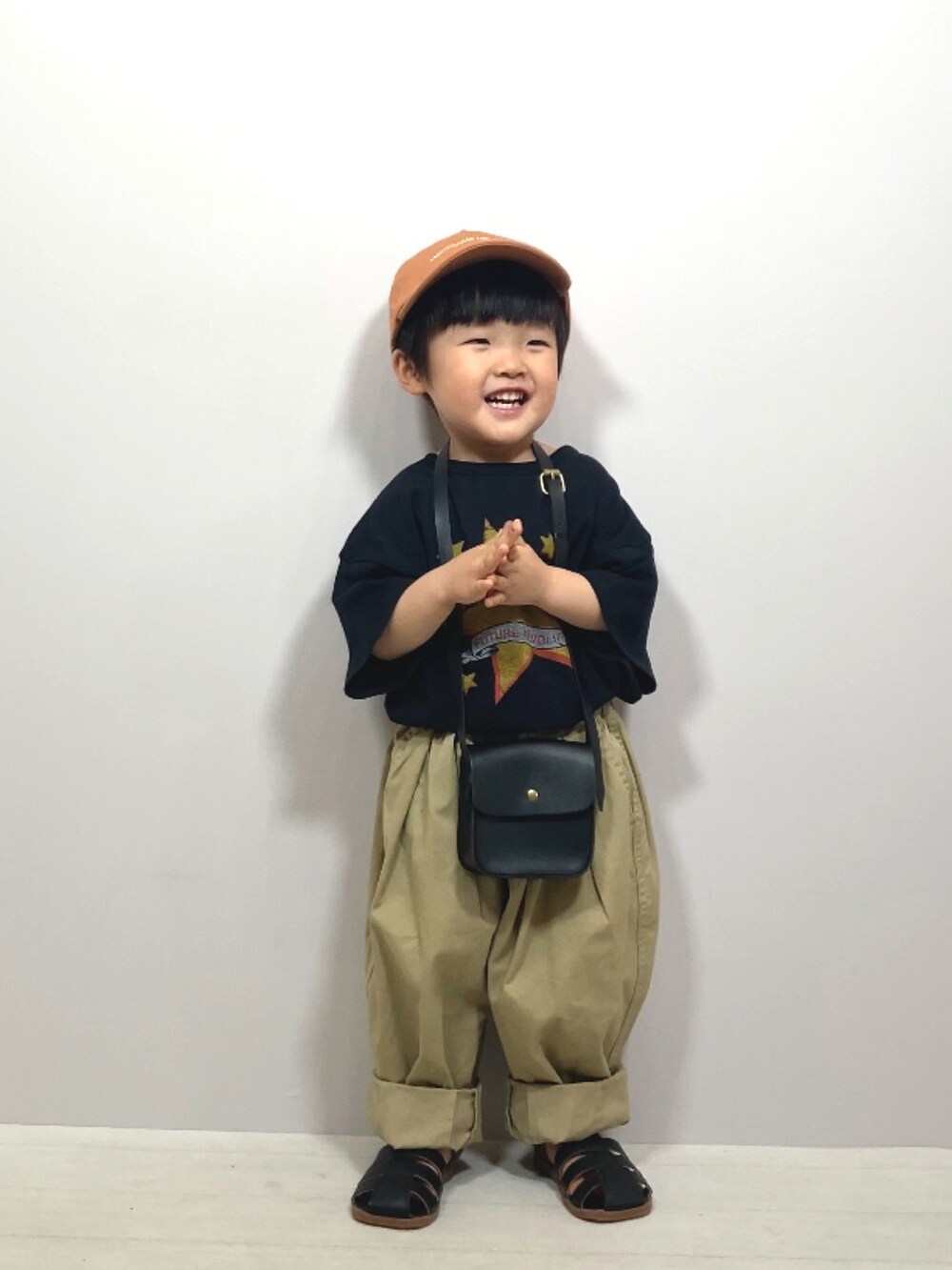 ブラック系のTシャツ/カットソー、ベージュ系のその他パンツ、ブラック系のショルダーバッグを着用したキッズの春コーディネートの2枚目の写真