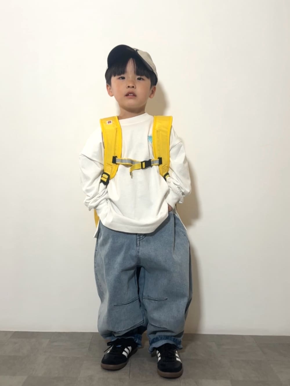 イエロー系のバックパック/リュック、ブラック系のスニーカー、ホワイト系のTシャツ/カットソーを着用したキッズの春コーディネートの4枚目の写真