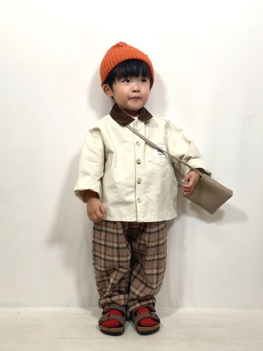 ホワイト系のジャケット/アウター、ブラウン系のパンツ、ベージュ系のショルダーバッグを着用したキッズの秋コーディネートの2枚目の写真