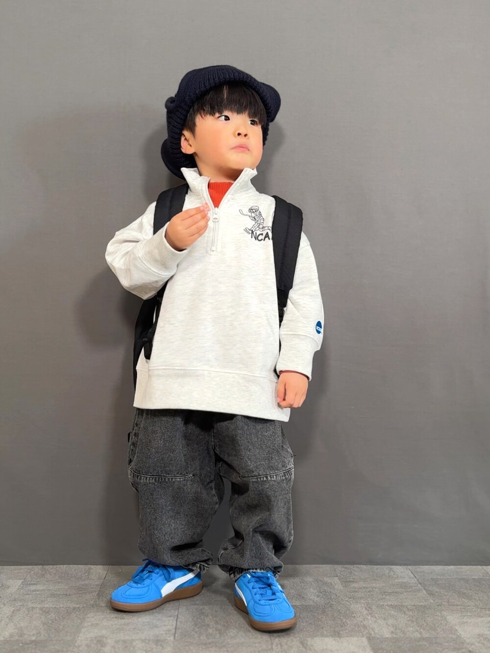 グレー系のスウェット、オレンジ系のTシャツ/カットソー、ブラック系のデニムパンツを着用したキッズの冬コーディネートの2枚目の写真