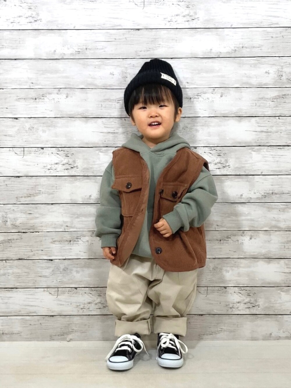 ブラウン系のベスト、グリーン系のスウェット、ホワイト系のその他パンツを着用したキッズの冬コーディネートの2枚目の写真