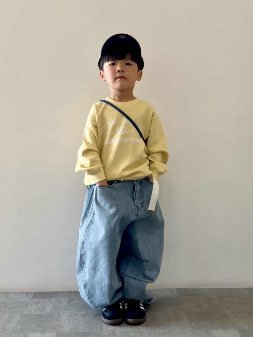 ブラック系のスニーカー、ブルー系のデニムパンツ、ブルー系のショルダーバッグを着用したキッズの春コーディネートの2枚目の写真