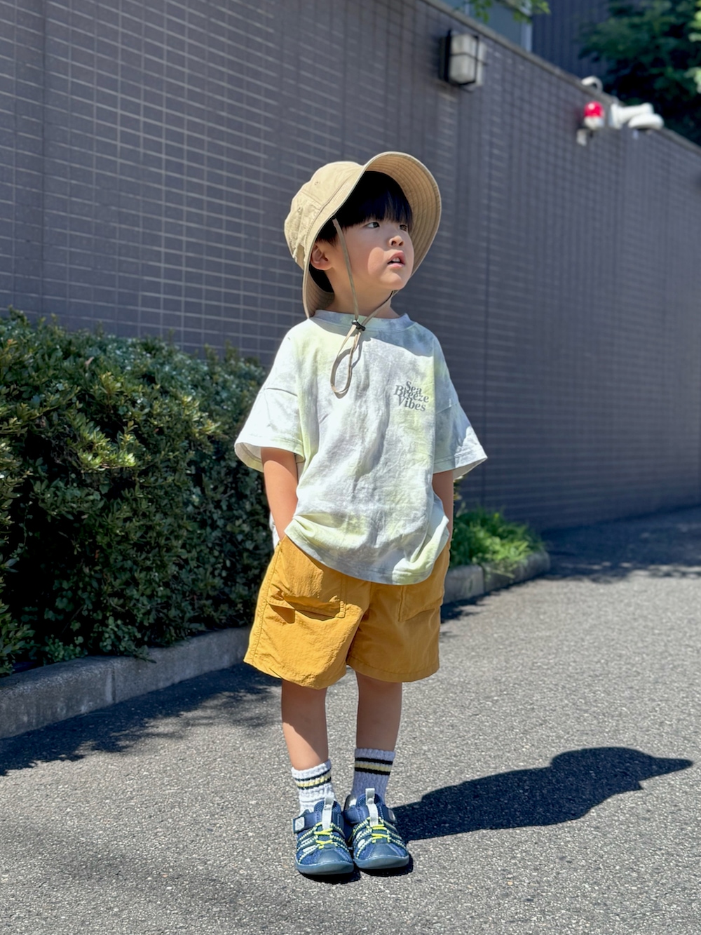 ブルー系のサンダル、グレー系のTシャツ/カットソー、イエロー系のパンツを着用したキッズの夏コーディネートの4枚目の写真