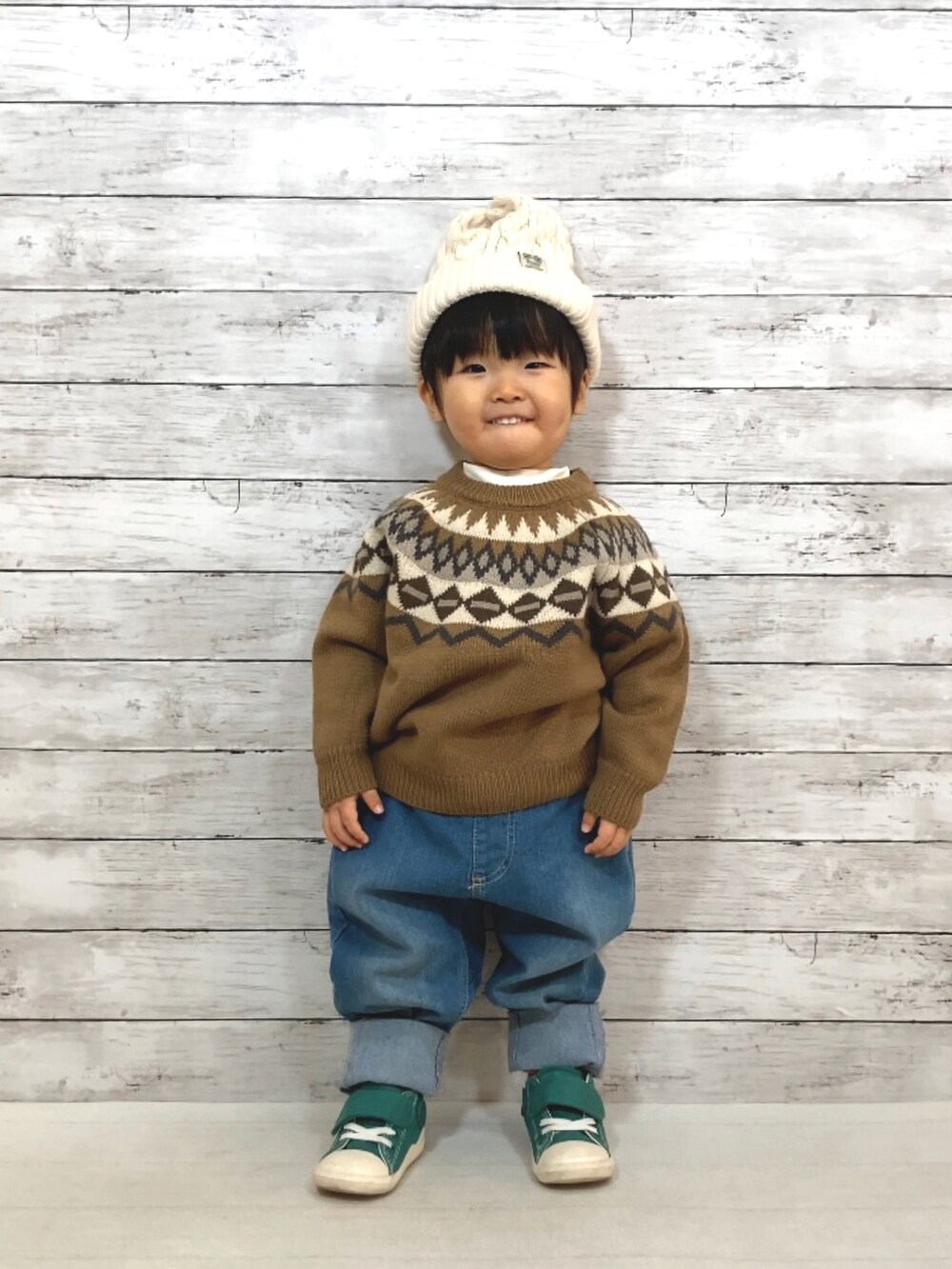 ブラウン系のニット/セーター、ホワイト系のTシャツ/カットソー、ブルー系のデニムパンツを着用したキッズの冬コーディネートの3枚目の写真