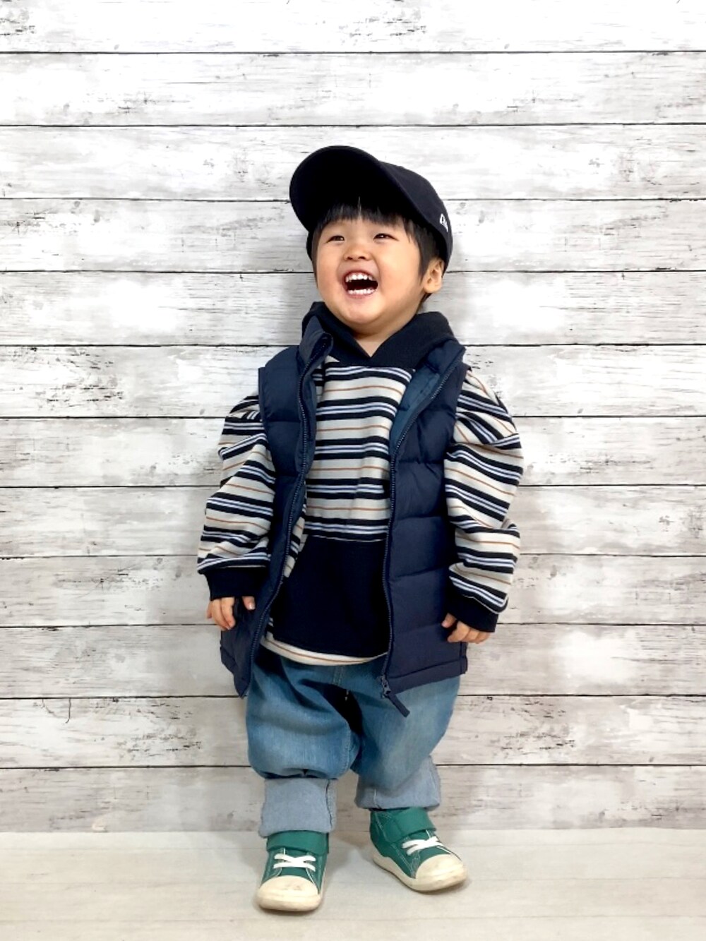 ブルー系のダウンベスト、ブラック系のパーカー、ブルー系のデニムパンツを着用したキッズの冬コーディネートの2枚目の写真
